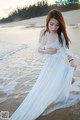 A woman in a white dress standing on a beach.