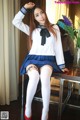 A woman in a school uniform sitting on a table.