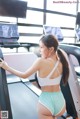 A woman in a white top and green shorts on a treadmill.