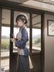 A woman in a blue kimono standing in front of a window.