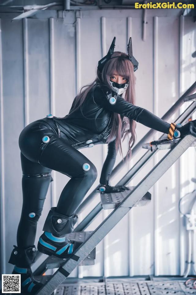 A woman in a black cat suit is climbing up a ladder.
