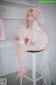 A woman in a white lingerie sitting on a stool.