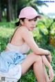 A woman in a pink hat sitting on the ground.