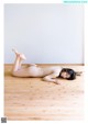 A naked woman laying on a wooden floor.