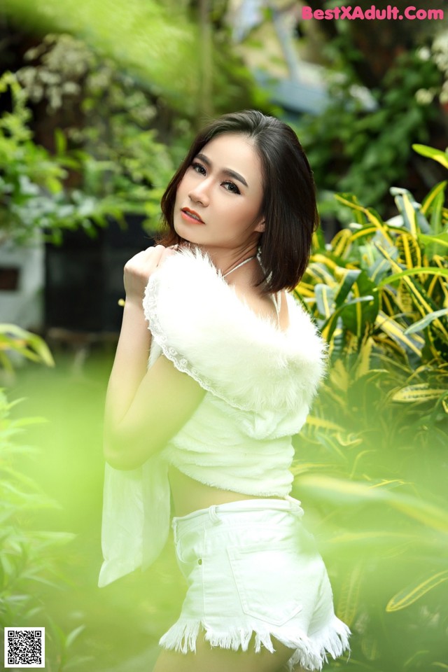 A woman in a white top and white shorts posing for a picture.
