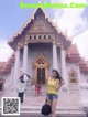 A woman standing in front of a temple holding an umbrella.