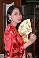 A woman in a red kimono holding a fan.