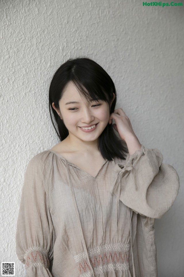 A woman standing in front of a white wall.
