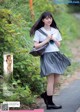 A young woman in a school uniform is walking down the road.