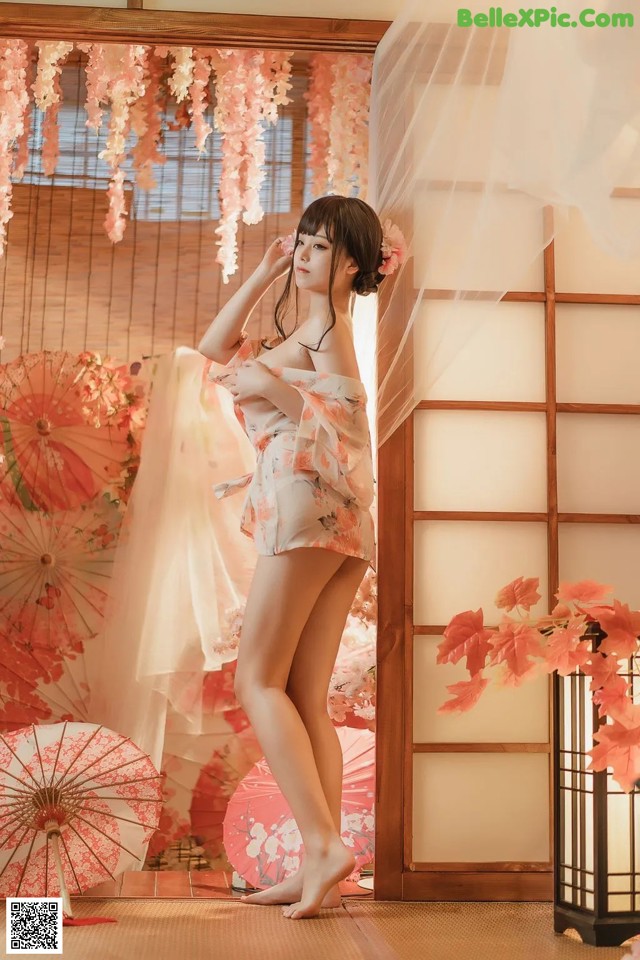 A woman in a kimono standing in front of a window.