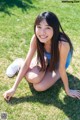 A young woman sitting on the grass in a park.