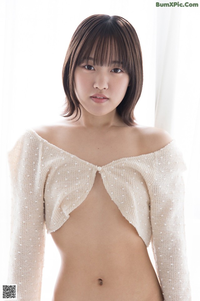 A woman in a white sweater is posing for a picture.